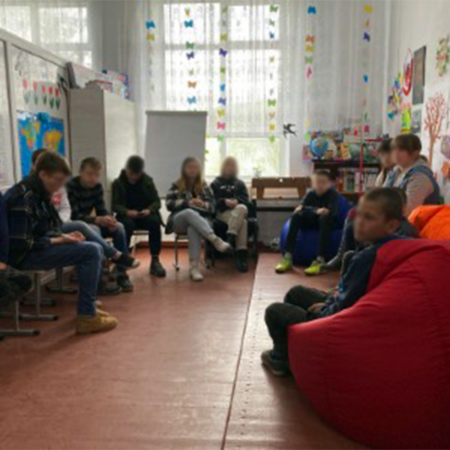 Group of refugee children sitting on chairs in a circle